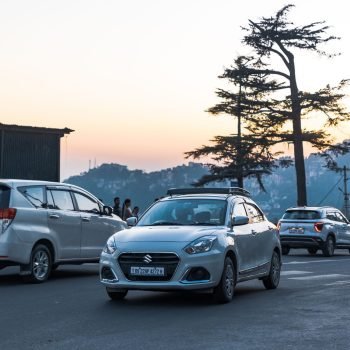 A serene evening cityscape featuring cars and people under a twilight sky.