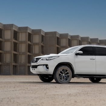 A white Toyota SUV parked in front of a concrete structure during sunset, highlighting its rugged design.