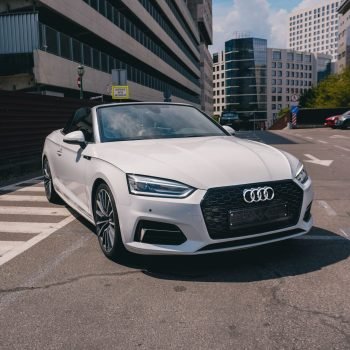 Modern white luxury car parked on a street in Kyiv, Ukraine during a sunny day.